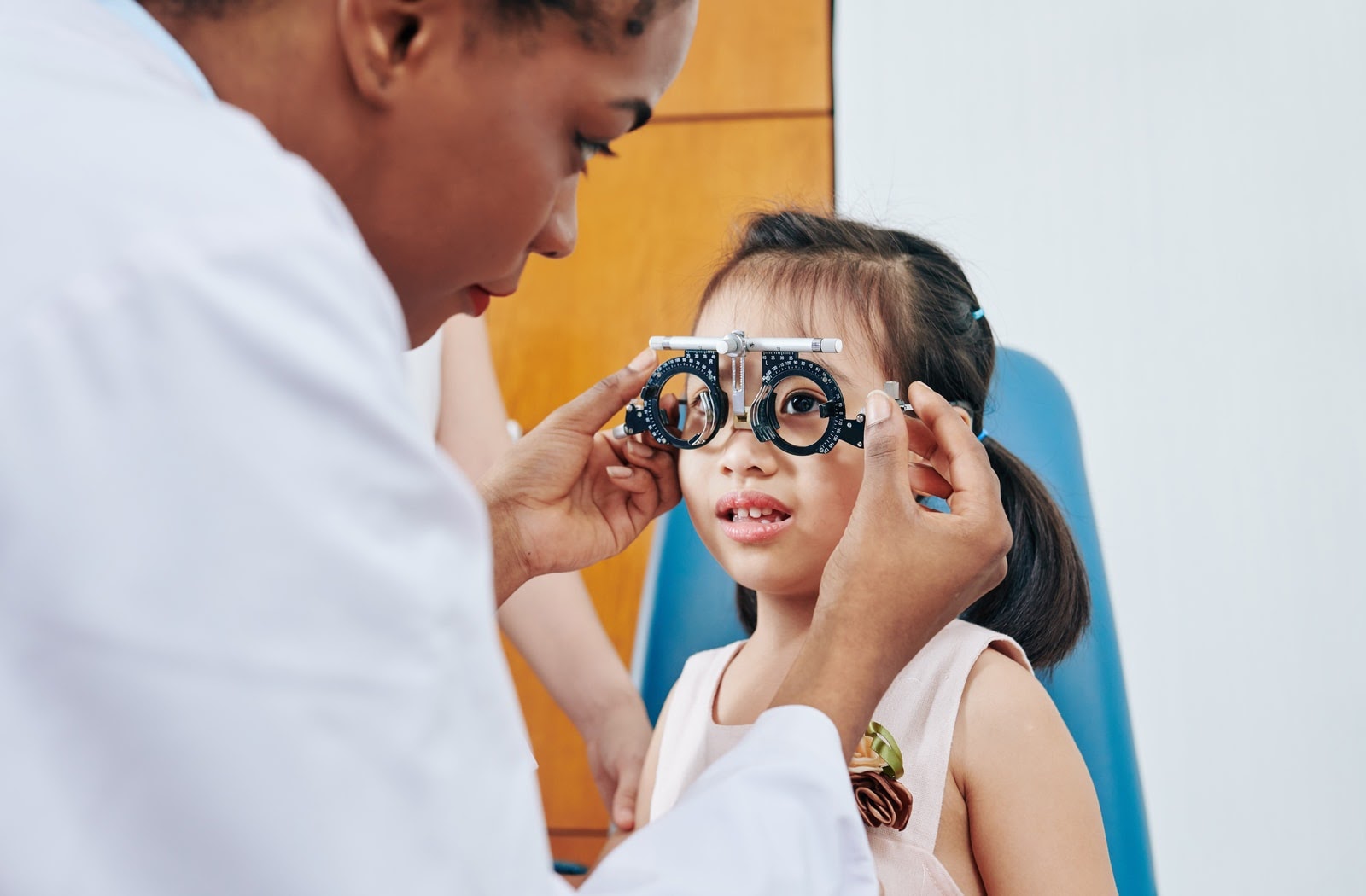 Young girl being fit for eyeglasses by an optician